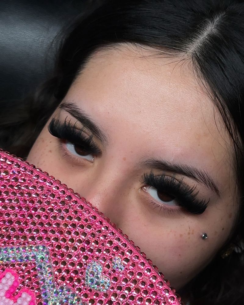 Wispy volume lashes behind a pink rhinestone Dallas Lash Trap bag